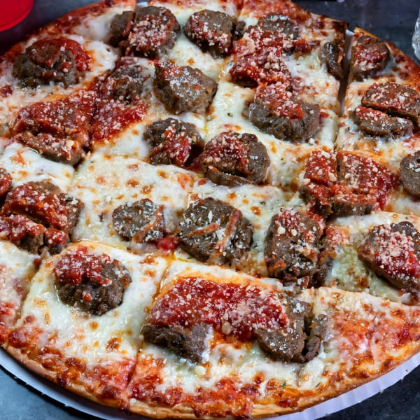Grapevine Pizza & Cafe's meatball pizza, topped with melted cheese, red sauce, and parmesan.