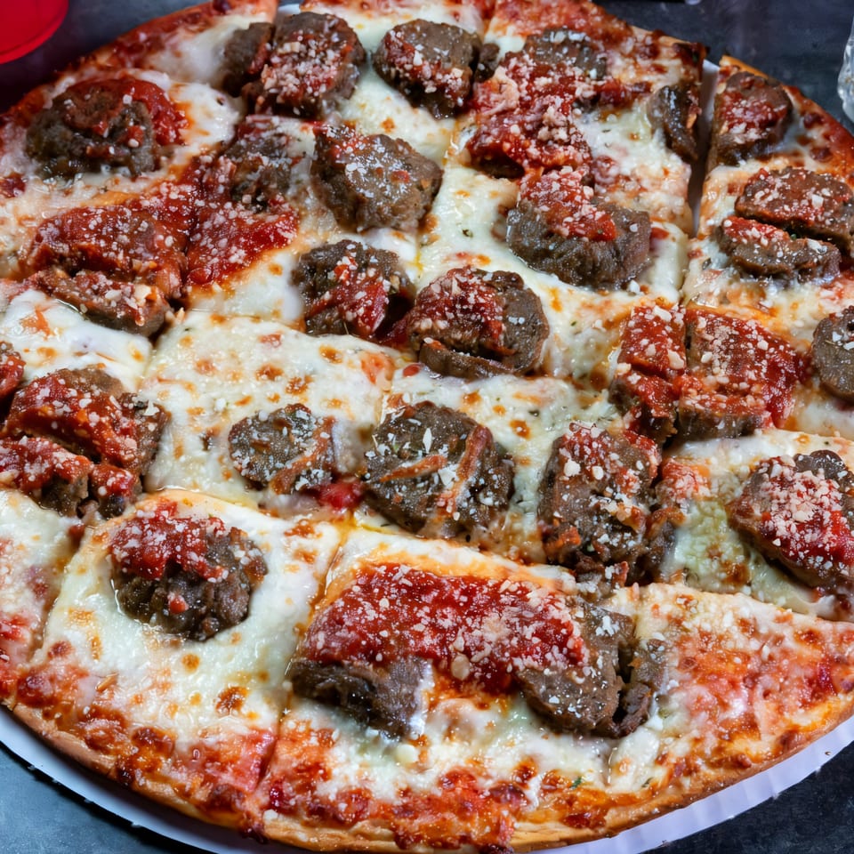 Grapevine Pizza & Cafe's meatball pizza, topped with melted cheese, red sauce, and parmesan.