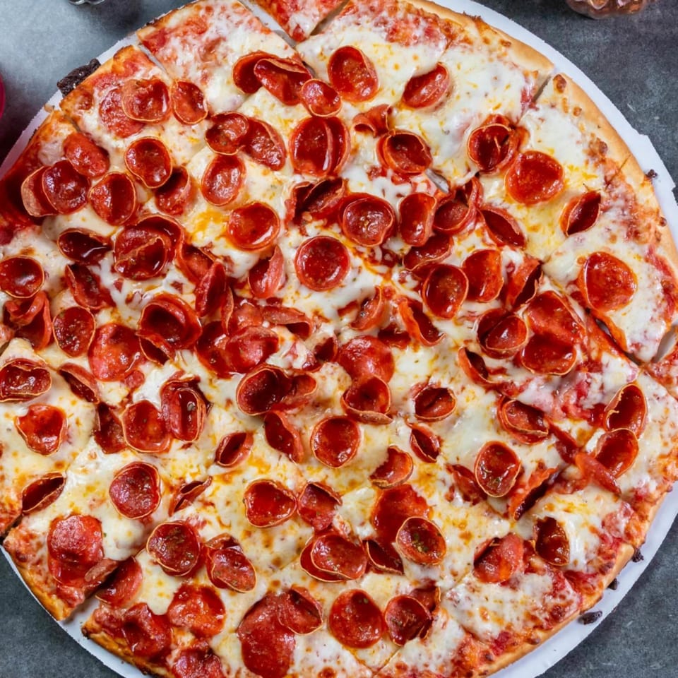 Close-up of a freshly baked, sliced pepperoni pizza from Grapevine Pizza & Cafe.