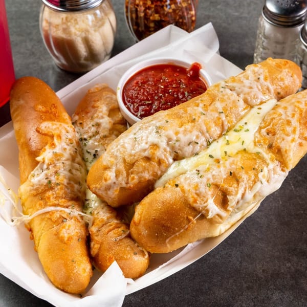 Cheesy garlic breadsticks with marinara dipping sauce, parmesan, and red pepper flakes from Grapevine Pizza & Cafe.